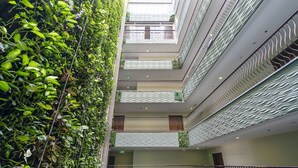 A multi-level atrium with a central staircase, balconies with railings, and a lush green wall. - Saigon Finest - IDG Suites Collection - 12J (Ho Chi Minh City)