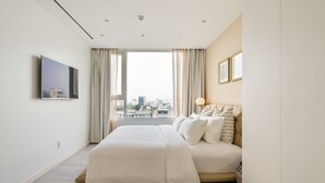 A modern hotel room with a large bed, a city view, and a flat-screen TV mounted on the wall. - Saigon Finest - IDG Suites Collection - 12K (Ho Chi Minh City)