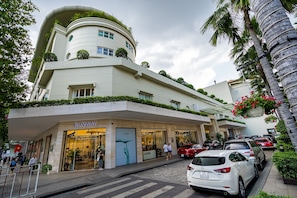 A modern building with a curved facade, a 'Runway' store on the ground floor, and a parking area with cars.