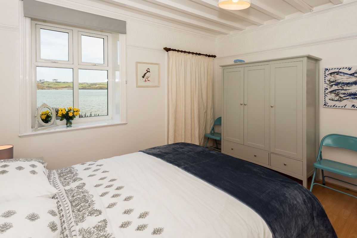 Une chambre à coucher avec un lit, une fenêtre donnant sur la mer, une armoire et une chaise.