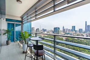 A balcony with a city view, potted plants, and a table and chairs. - Saigon Skyline Suite in Central District 1 (Ho Chi Minh City)