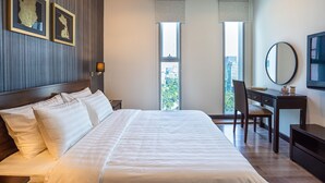 A hotel room with a large bed, a desk, a chair, and a view of the city through the windows. - Saigon Skyline Suite in Central District 1 (Ho Chi Minh City)