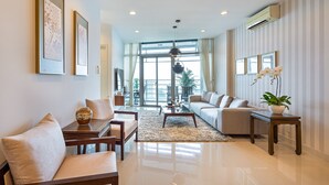 A modern living room with a sofa, coffee table, and chairs, a large window with curtains, and a potted plant. - Sai Gon Finest - Panorama Suite in Central D1 (Ho Chi Minh City)