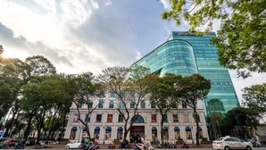 A historic building with a large arched entrance and a modern glass skyscraper in the background. - Sai Gon Finest - Panorama Suite in Central D1 (Ho Chi Minh City)