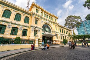 Ein historisches Gebäude mit einem Glockenturm, grünen Fensterläden und einer gepflasterten Straße.