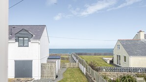A coastal residential area with houses, a grassy lawn, and a view of the sea.