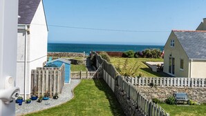 A coastal property with a view of the sea, a fenced garden, and a small pool.