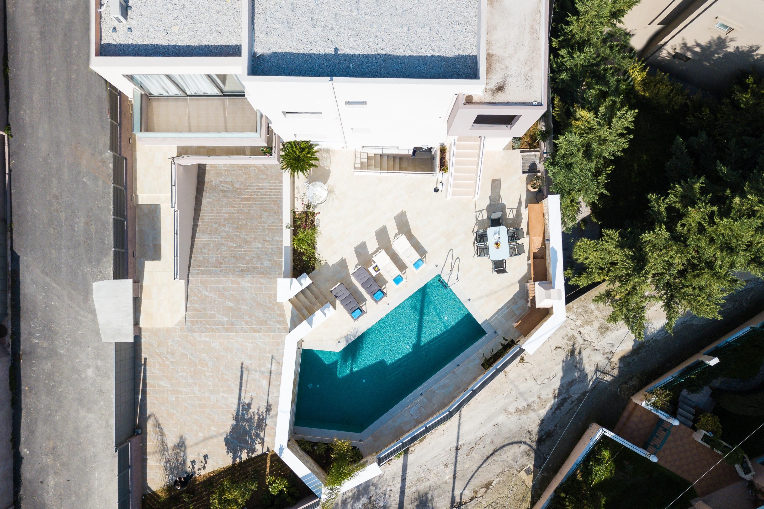 Vista aérea de un edificio moderno con piscina, mobiliario exterior y una escalera.