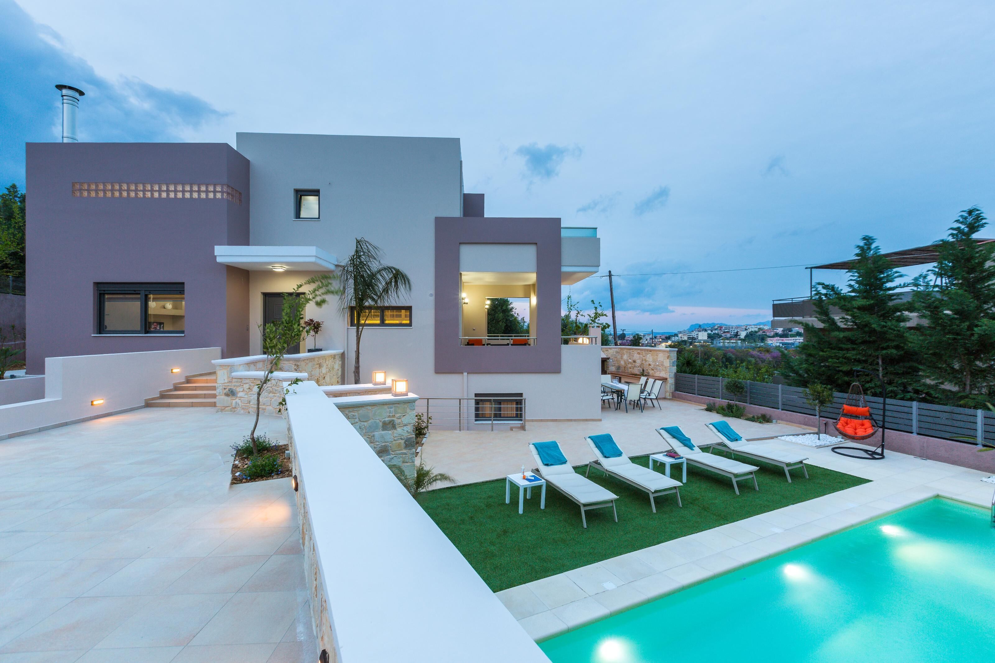 Ein modernes Haus mit Swimmingpool, Sitzgelegenheiten im Freien und Blick auf die Stadt.