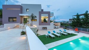 A modern house with a swimming pool, outdoor seating, and a view of the city. - Peris Villa (Chania)