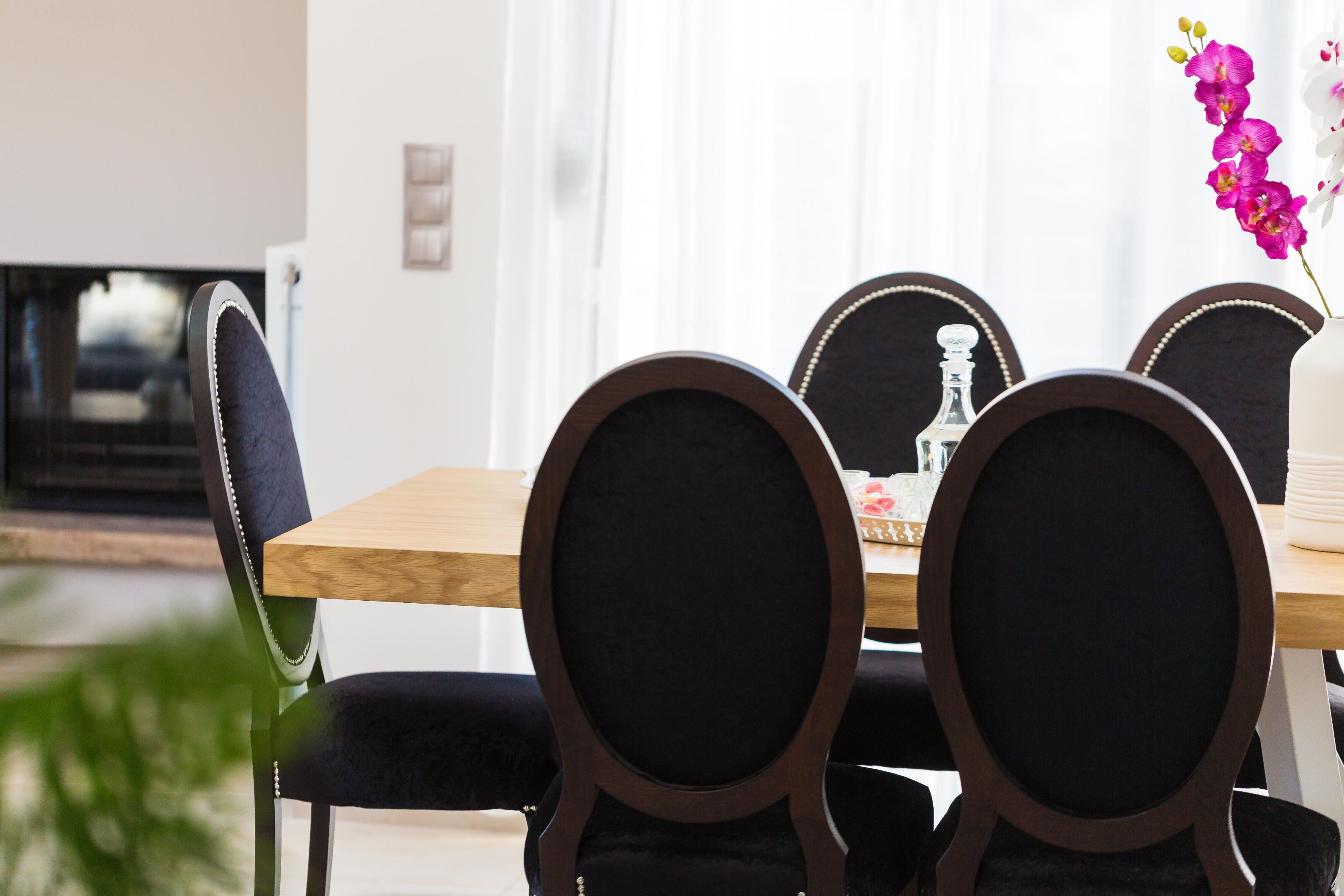 A dining area with a wooden table and black upholstered chairs.