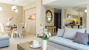 A modern living room with a dining area, a kitchen in the background, and a balcony with a glass railing. - Peris Villa (Chania)