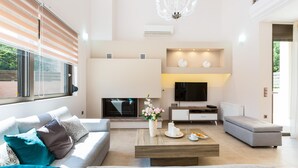 A modern living room with a sofa, coffee table, and TV. - Peris Villa (Chania)
