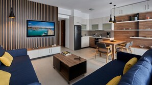 A modern living room with a TV, sofa, coffee table, and a dining area with chairs and a table. - Thalita Cozy Apartment (Heraklion)
