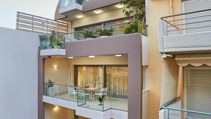 A modern multi-story building with balconies, glass railings, and outdoor seating areas. - Thalita Cozy Apartment (Heraklion)