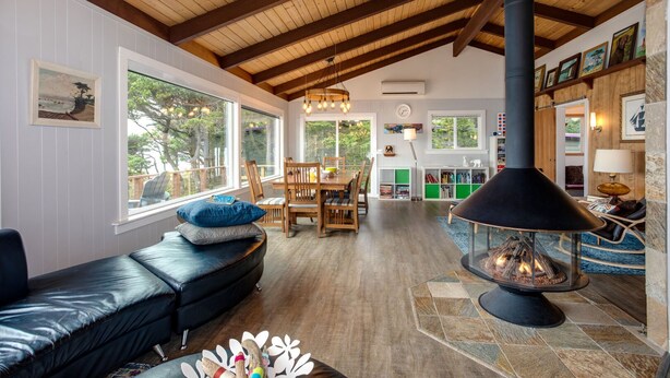 Una sala de estar acogedora con chimenea, vigas de madera en el techo y ventanas amplias.
