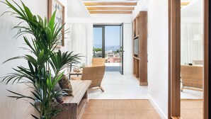 Ein modernes Wohnzimmer mit einer großen Pflanze, Korbmöbeln und Blick ins Freie.