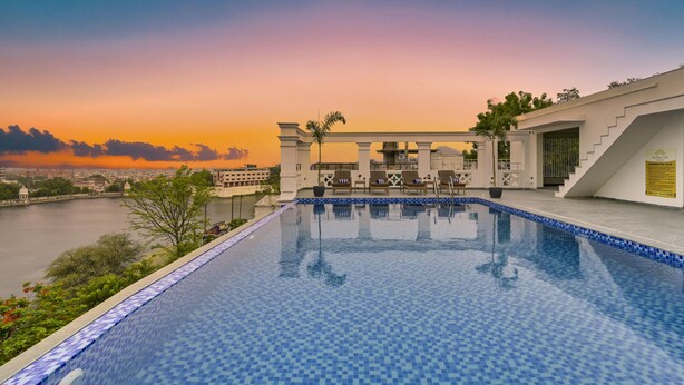 A rooftop infinity pool with a view of the city skyline at sunset. - Brahma Niwas - Luxury Lake View Hotel with Infinity Pool, Udaipur  (Udaipur)