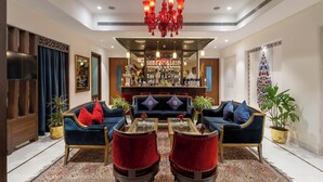 A modern living room with a bar area, featuring sofas, armchairs, and a chandelier. - Brahma Niwas - Luxury Lake View Hotel with Infinity Pool, Udaipur  (Udaipur)