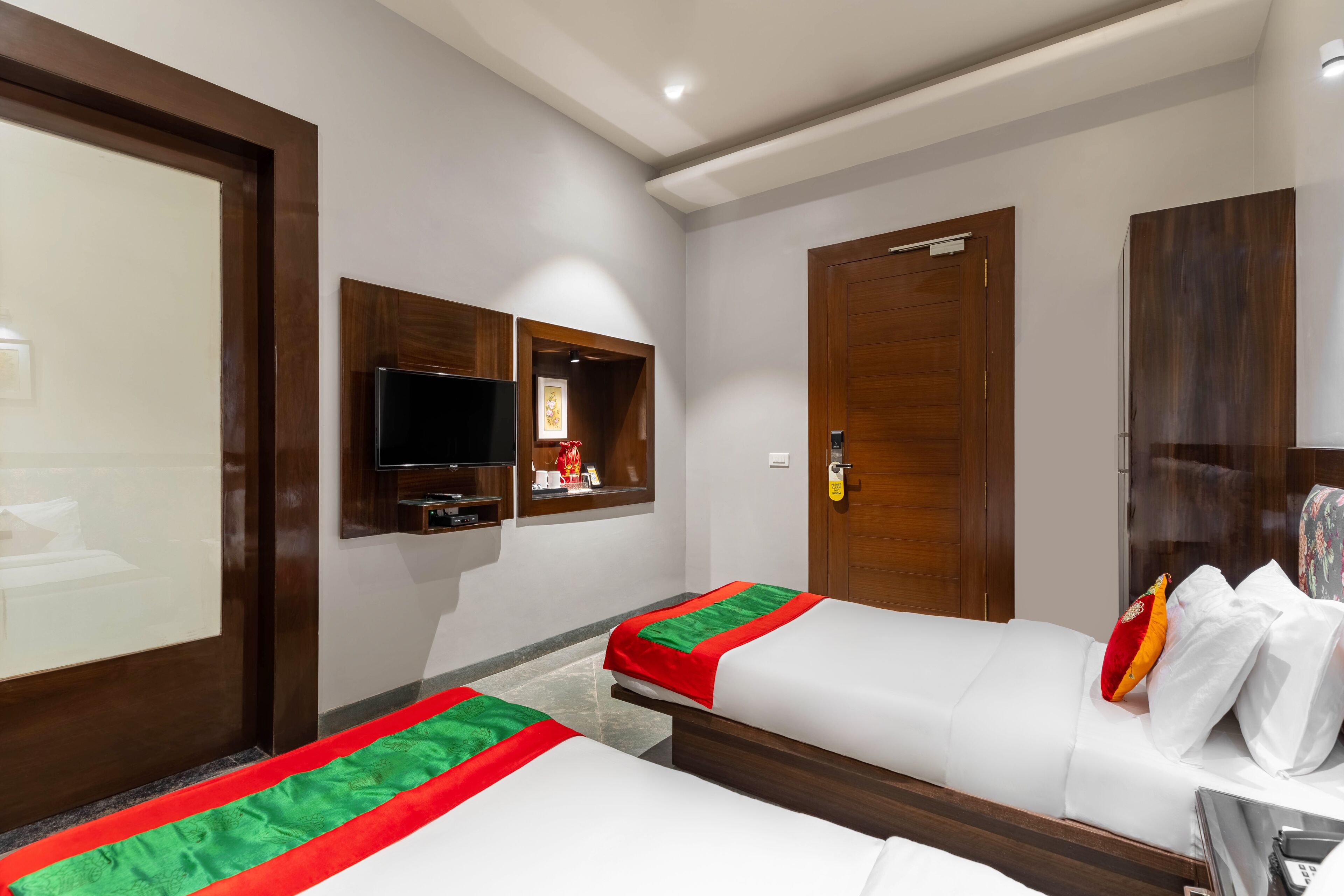 Een hotelkamer met twee bedden, een televisie, een kast en een spiegel.