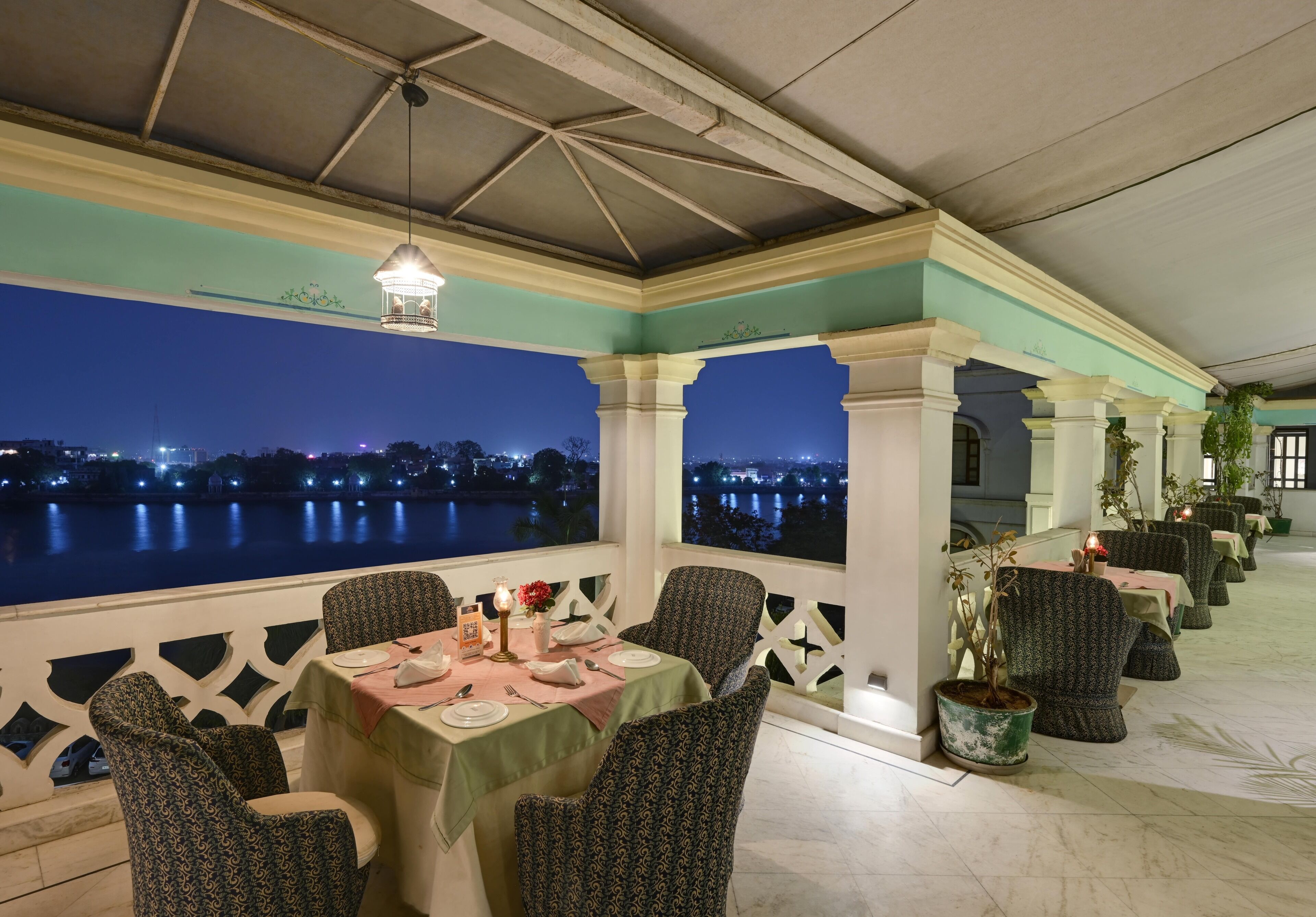 A restaurant with a terrace overlooking a body of water at night.
