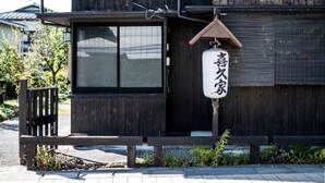 Een houten gebouw met een groot raam en een hangbord met Japanse tekens.