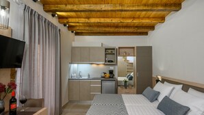 Een compacte hotelkamer met een bed, nachtkastje en een kleine kitchenette.