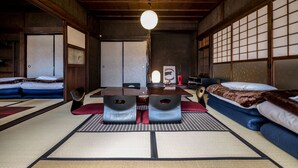 Una habitación japonesa tradicional con suelo de tatami, una mesa baja de madera, dos esterillas de tatami con cojines y puertas correderas.