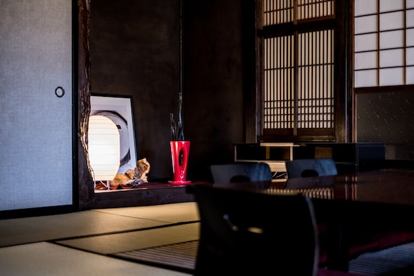 A traditional Japanese room with tatami flooring, a low table, and a sliding door.