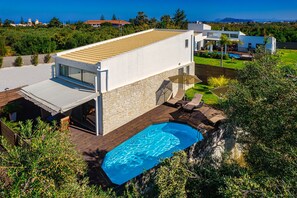 A modern house with a swimming pool, a covered patio, and a view of the surrounding landscape. - Cocoon Villas (Platanias)