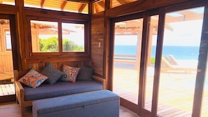 Una terraza de madera con zona de estar acolchada y vista al océano.
