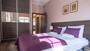 Una habitación de hotel con una cama grande, un armario y una puerta que da a un baño.