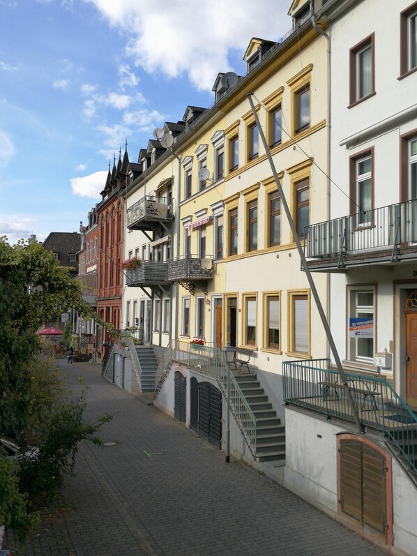 A row of traditional European buildings with balconies, a cobblestone street, and a clear sky. - Romantisch wohnen in Kaub am Rhein (Kaub)