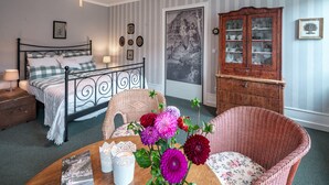 A neatly arranged bedroom with a bed, dresser, and a dining table with flowers. - Romantisch wohnen in Kaub am Rhein (Kaub)