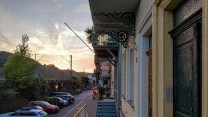 A street view with parked cars, a staircase leading to a building, and a hillside in the background. - Romantisch wohnen in Kaub am Rhein (Kaub)