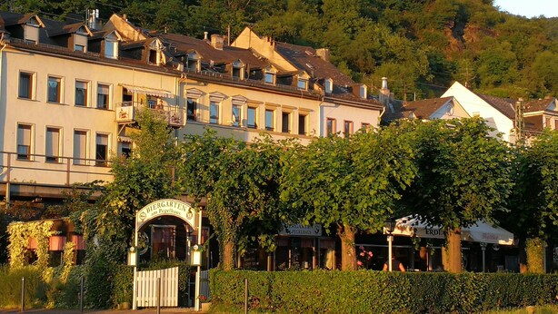 A traditional European building with a sign indicating it is a Biersgarten, surrounded by lush greenery and hills in the background. - Romantisch wohnen in Kaub am Rhein (Kaub)