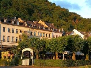 A traditional European building with a sign indicating it is a Biersgarten, surrounded by lush greenery and hills in the background. - Romantisch wohnen in Kaub am Rhein (Kaub)