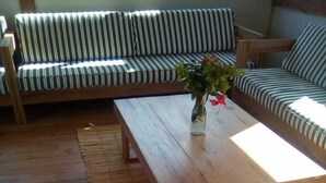 Un plancher en bois, un grand canapé et une table basse dans une pièce baignée de lumière naturelle.