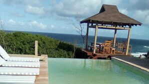 Une terrasse en bois avec des chaises longues et une piscine.