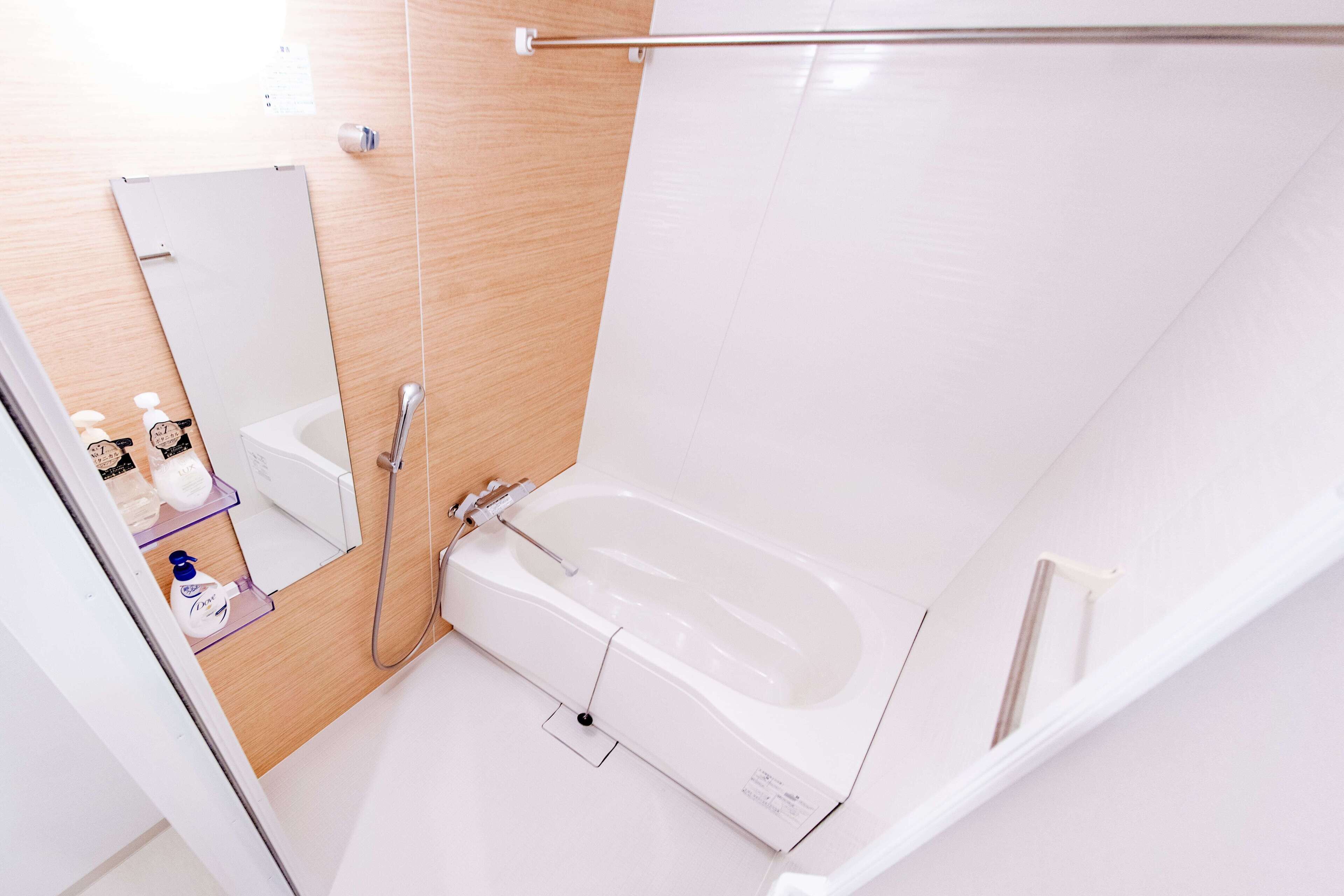 A modern bathroom with a bathtub, a shower, and a mirror.
