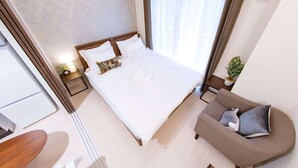 Moderni hotellihuone, jossa on suuri sänky, sohva ja pieni pöytä.