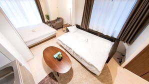 Hotellihuone, jossa on suuri sänky, pieni työpöytä, tuoli ja sohva.