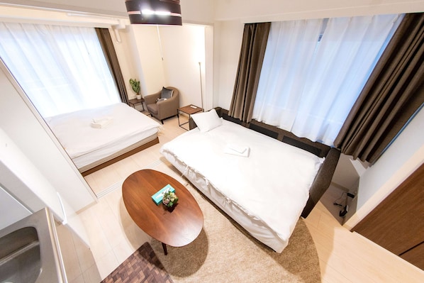 A hotel room with a large bed, a small desk, a chair, and a sofa.
