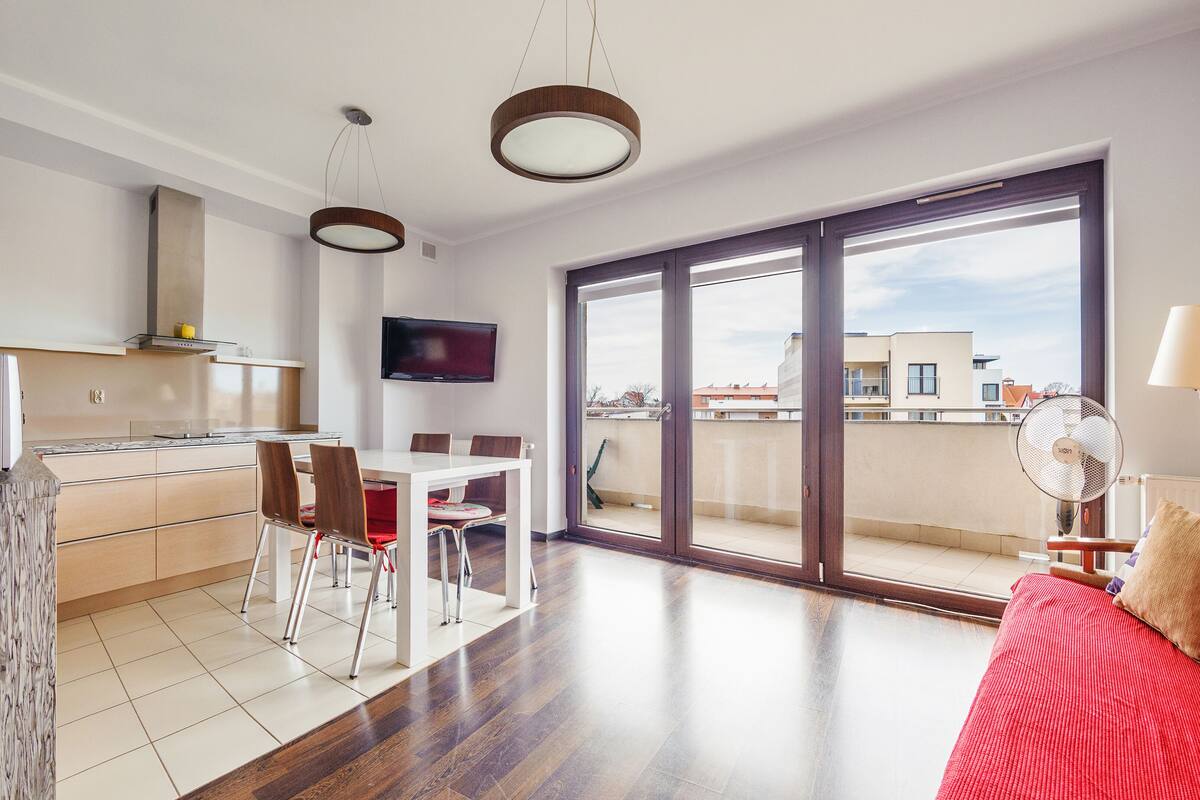 A modern apartment with a kitchen, dining area, and a balcony with a view.