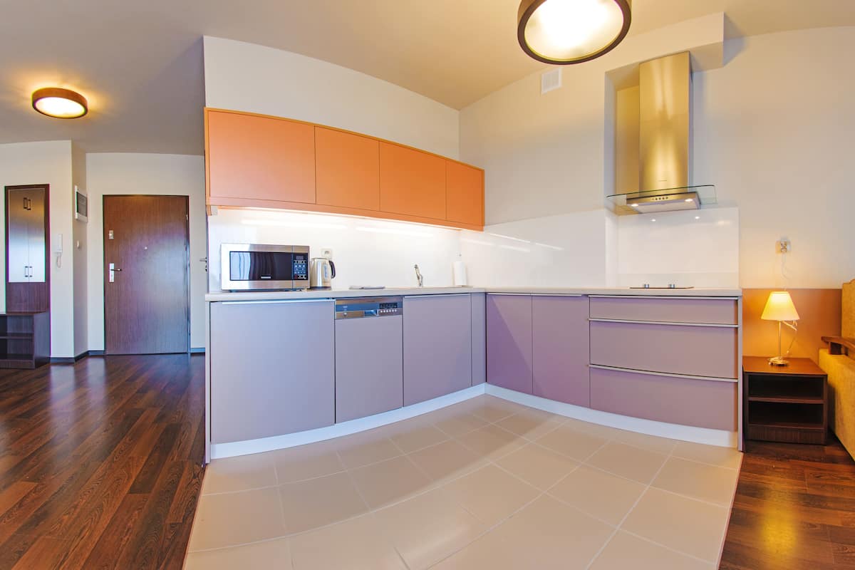 A modern kitchen with a microwave, dishwasher, and orange cabinets.