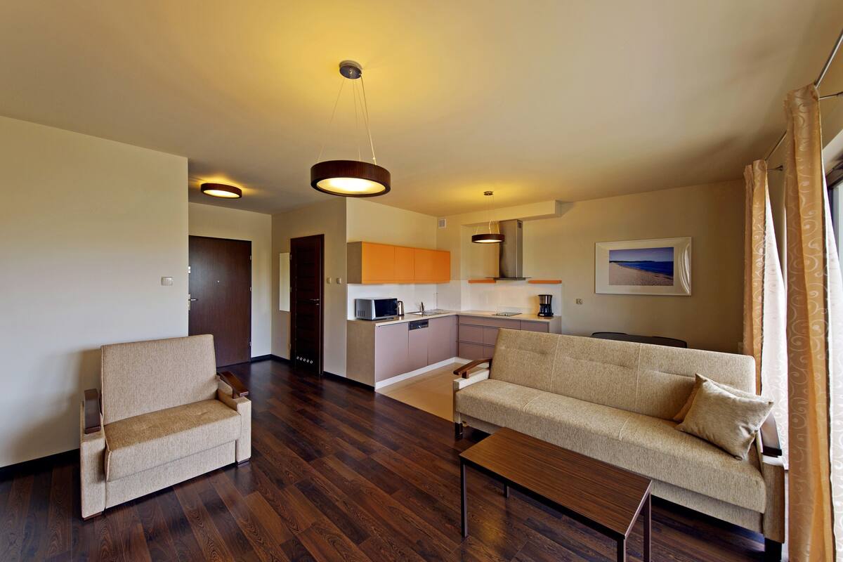 A modern living room with a sofa, a coffee table, and a kitchen area in the background.