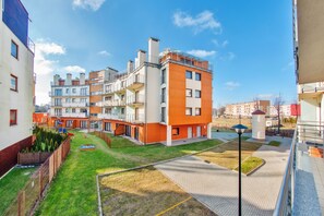 A residential building with multiple balconies, a courtyard with a playground, and a clear sky. - Apartamenty Sun & Snow Foka (Hel)