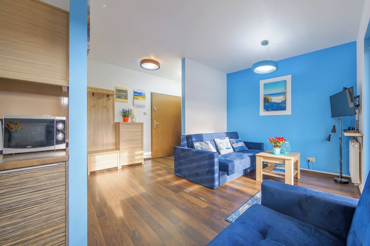 A modern living room with a blue sofa, a wooden coffee table, and a television.