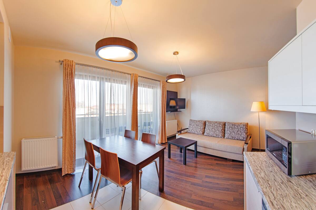 A modern living room with a dining table, sofa, and kitchen area.