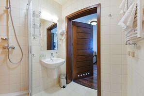 A modern bathroom with a shower, sink, and wooden door. - Apartamenty Sun & Snow Foka (Hel)